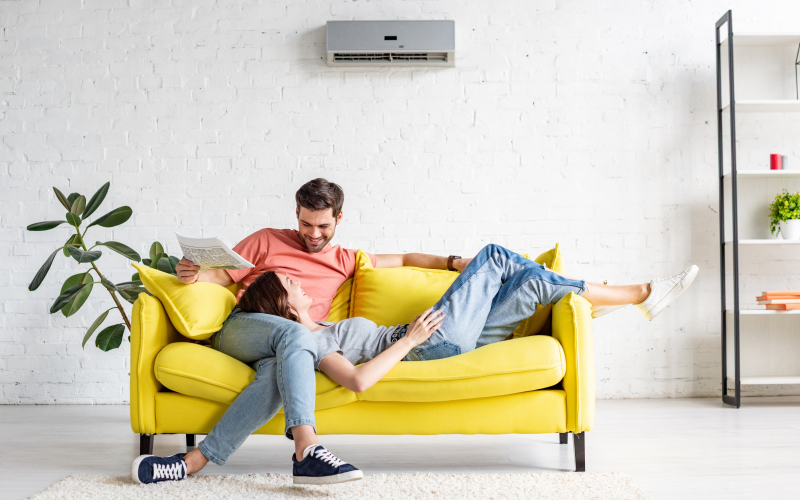 Happy,Man,With,Smiling,Girlfriend,Relaxing,On,Yellow,Sofa,Under